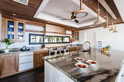 a kitchen with wooden cabinets and a large marble counter top at The Point Luxury Villa, Tamarindo in Tamarindo