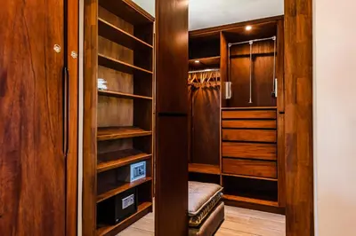 a walk in closet with wooden cabinets and a bench at The Point Luxury Villa, Tamarindo in Tamarindo