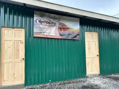 a green building with two doors and a banner on it at Camping El Fosforo in El Fosforo