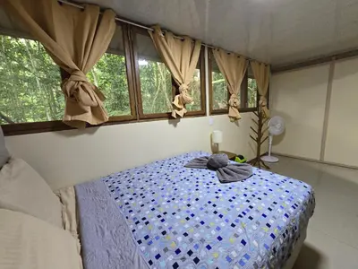 a bedroom with a bed in a room with windows at Cool Waters Jungle Hostel in Uvita