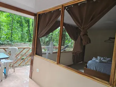a room with a window with a bed and a balcony at Cool Waters Jungle Hostel in Uvita