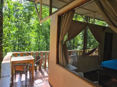 a screened in porch with a table and chairs at Cool Waters Jungle Hostel in Uvita