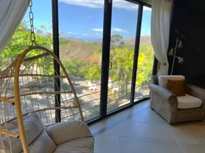 a living room with a couch and a large window at Casa del Artista 4bed,4 bath Ocean view home in Playa Hermosa