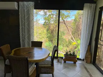 a dining room with a table and a large window at Casa del Artista 4bed,4 bath Ocean view home in Playa Hermosa