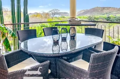 a glass table with four vases on a balcony at Casa del Artista 4bed,4 bath Ocean view home in Playa Hermosa