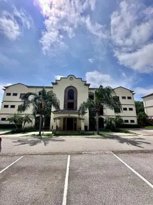 a large white building with palm trees in a parking lot at Palmas de Tamarindo Resort, 304E in Guanacaste