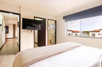 a bedroom with a white bed and a flat screen tv at Palmas de Tamarindo Resort, 304E in Guanacaste