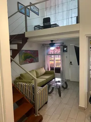 a living room with a staircase and a green couch at Enchanting 3 BR 2 Bath Condo in the Heart of Jaco in Jacó