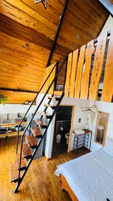 a staircase in a room with a bed and wooden ceilings at Hotel en Huacas y Brasilito in Matapalo