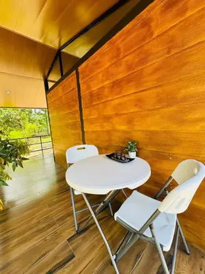 two chairs and a table in a room with wooden walls at Cabañas La Hermosa #1 in Guápiles