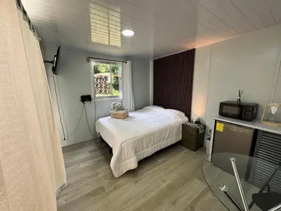 a bedroom with a bed and a window and a television at Cedro lodge in Fraijanes