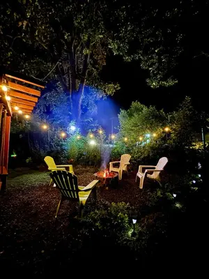 a group of chairs and a table in a yard at night at Cedro lodge in Fraijanes