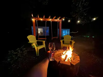 a fire pit with two chairs and a table with a glass at Cedro lodge in Fraijanes
