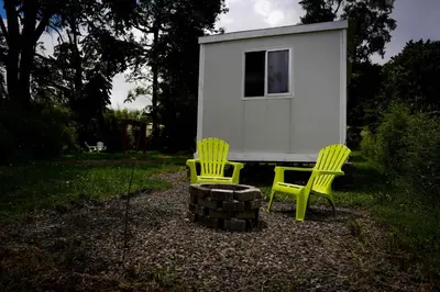 two green chairs and a fire pit in front of a tiny house at Cedro lodge in Fraijanes