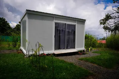 a white shed with a window in a yard at Cedro lodge in Fraijanes