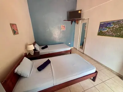 a room with two beds and a tv on the wall at Casitas de la Paz in Coco