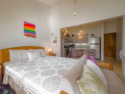 a bedroom with a large bed and a kitchen at Emerald Haven Second Floor Studio Mins from Beach in Coco