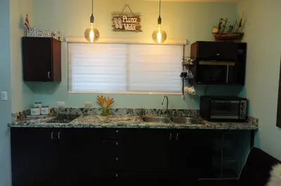 a kitchen with a sink and a microwave and a window at Marine Beach Bliss Ground Floor Studio in Coco