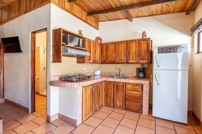 a kitchen with wooden cabinets and a white refrigerator at Cozy Beachside Studio with Pool and Free WiFi in Playa Grande