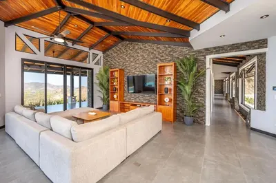 a living room with a couch and a tv at Luxurious Mountaintop Retreat with Ocean Views in Matapalo
