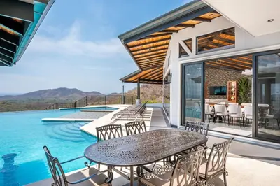 a patio with a table and chairs next to a pool at Luxurious Mountaintop Retreat with Ocean Views in Matapalo