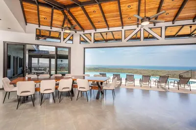 a dining room with a table and chairs and the ocean at Luxurious Mountaintop Retreat with Ocean Views in Matapalo