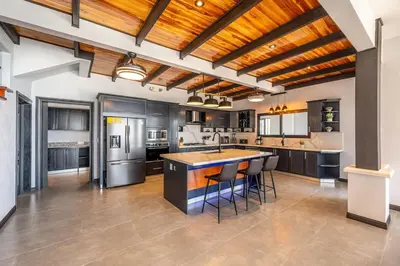 a large kitchen with black cabinets and a wooden ceiling at Luxurious Mountaintop Retreat with Ocean Views in Matapalo