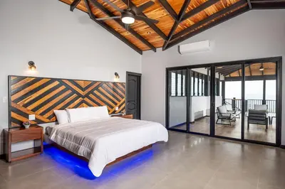 a bedroom with a large bed and a balcony at Luxurious Mountaintop Retreat with Ocean Views in Matapalo