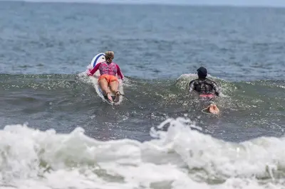 a woman riding a wave on a surfboard in the ocean at BeachBungalow Surf&Stay in Patos