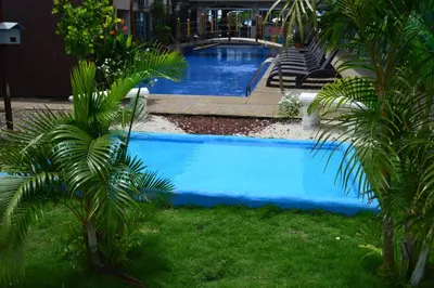 a swimming pool in a yard with palm trees at Beachfront Hotel Tramonto in Jacó