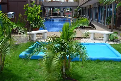 a swimming pool with two benches and a palm tree at Beachfront Hotel Tramonto in Jacó