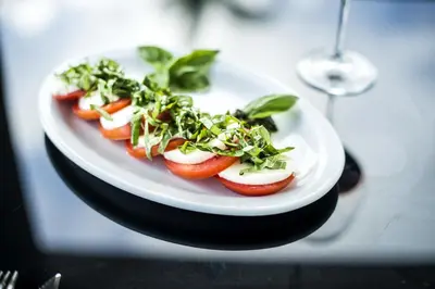 a plate of food with tomatoes and greens on a table at Beachfront Hotel Tramonto in Jacó