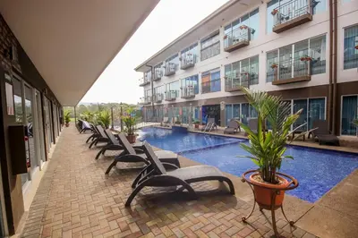 a row of chairs next to a building with a pool at Beachfront Hotel Tramonto in Jacó