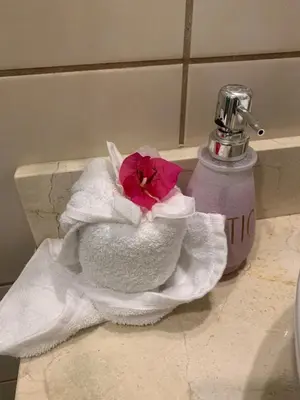 a pink flower in a towel on a bathroom sink at Casa Limonada Ground Condo in Coco