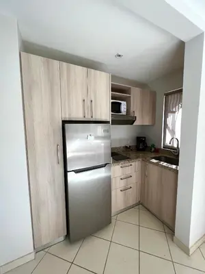 a kitchen with a refrigerator and wooden cabinets at The Nest 2 bedroom1 bath Condo Rooftop patio in Coco