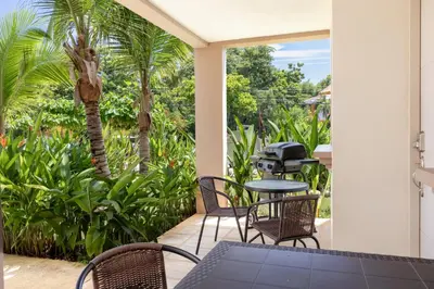a patio with a table and chairs and palm trees at Two Palms Ground Floor Unit Across from Beach in Coco