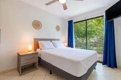 a bedroom with a bed and a large window at Two Palms Ground Floor Unit Across from Beach in Coco