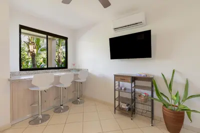 a living room with two bar stools and a flat screen tv at Two Palms Ground Floor Unit Across from Beach in Coco