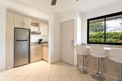 a kitchen with a stainless steel refrigerator and white cabinets at Two Palms Ground Floor Unit Across from Beach in Coco