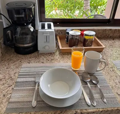 a table with a plate and a cup of orange juice at Two Palms Ground Floor Unit Across from Beach in Coco