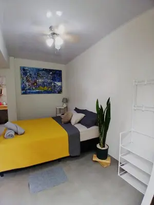 a bedroom with a large yellow bed and a plant at SJO Green Casita in Santiago Este