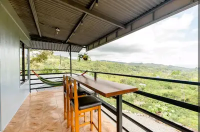 a balcony with a table and chairs and a hammock at CANTO DEL RIO-Rivas- vista a la montaña- tranquilo in Rivas