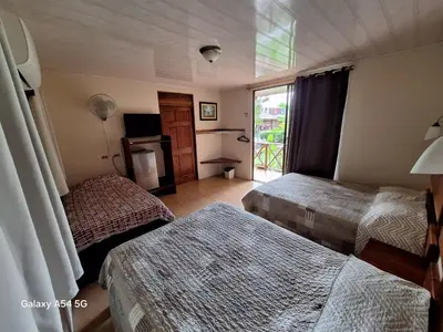 a hotel room with two beds and a window at Hotel Iris Arenal in Fortuna