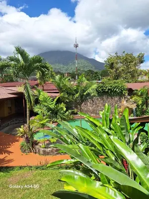 a resort with a swimming pool and mountains in the background at Hotel Iris Arenal in Fortuna