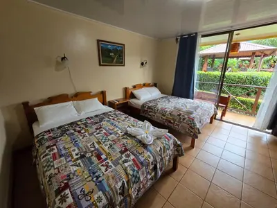 a hotel room with two beds and a balcony at Hotel Iris Arenal in Fortuna