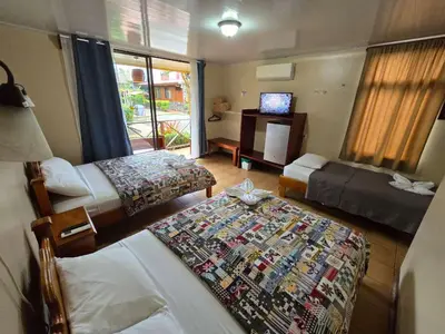 a hotel room with two beds and a television at Hotel Iris Arenal in Fortuna