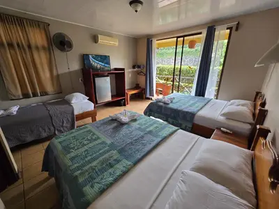 a hotel room with two beds and a television at Hotel Iris Arenal in Fortuna