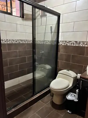 a bathroom with a toilet and a glass shower at Apartamento Caribe Rosa in Puerto Limón