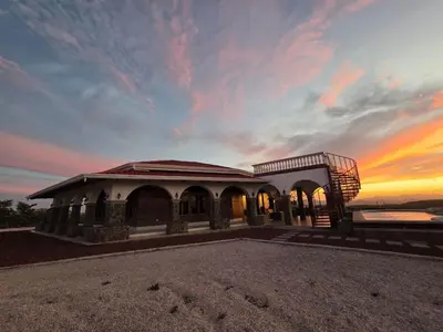 a building with a sunset in the background at Casona Cocobolo el mejor lugar de Costa Rica in Guanacaste