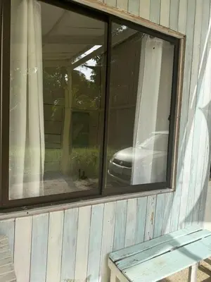 a window on the side of a house with a car at Hostel Los Pargos in Río Sequito